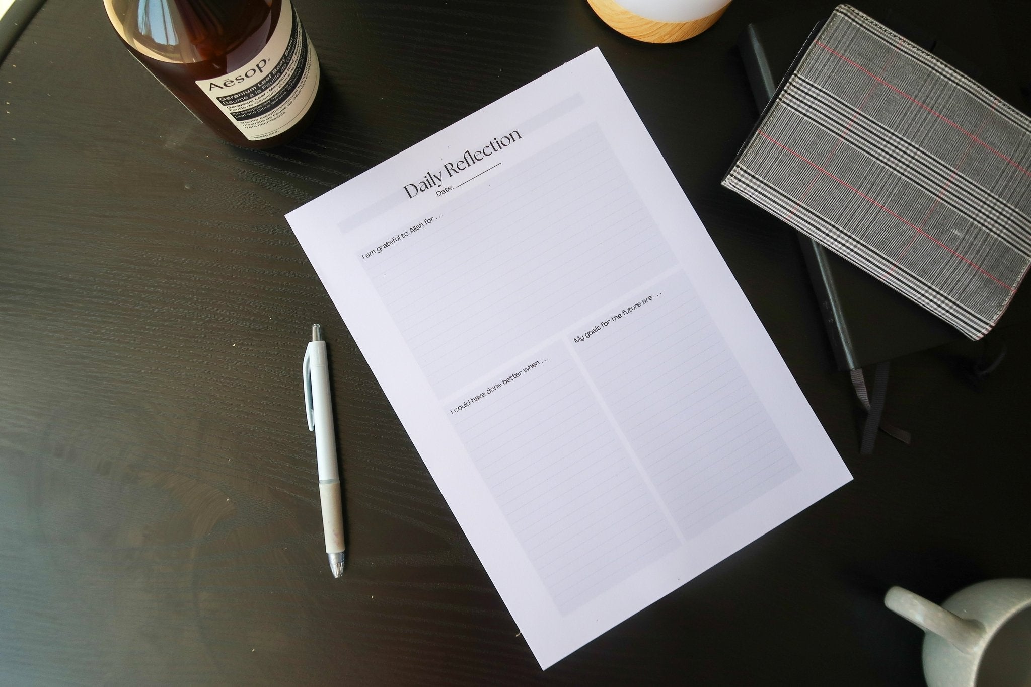 Totepad's A4 Luxury Daily Reflection Notepad on a black table, tastefully laid out with a planner and stationery.